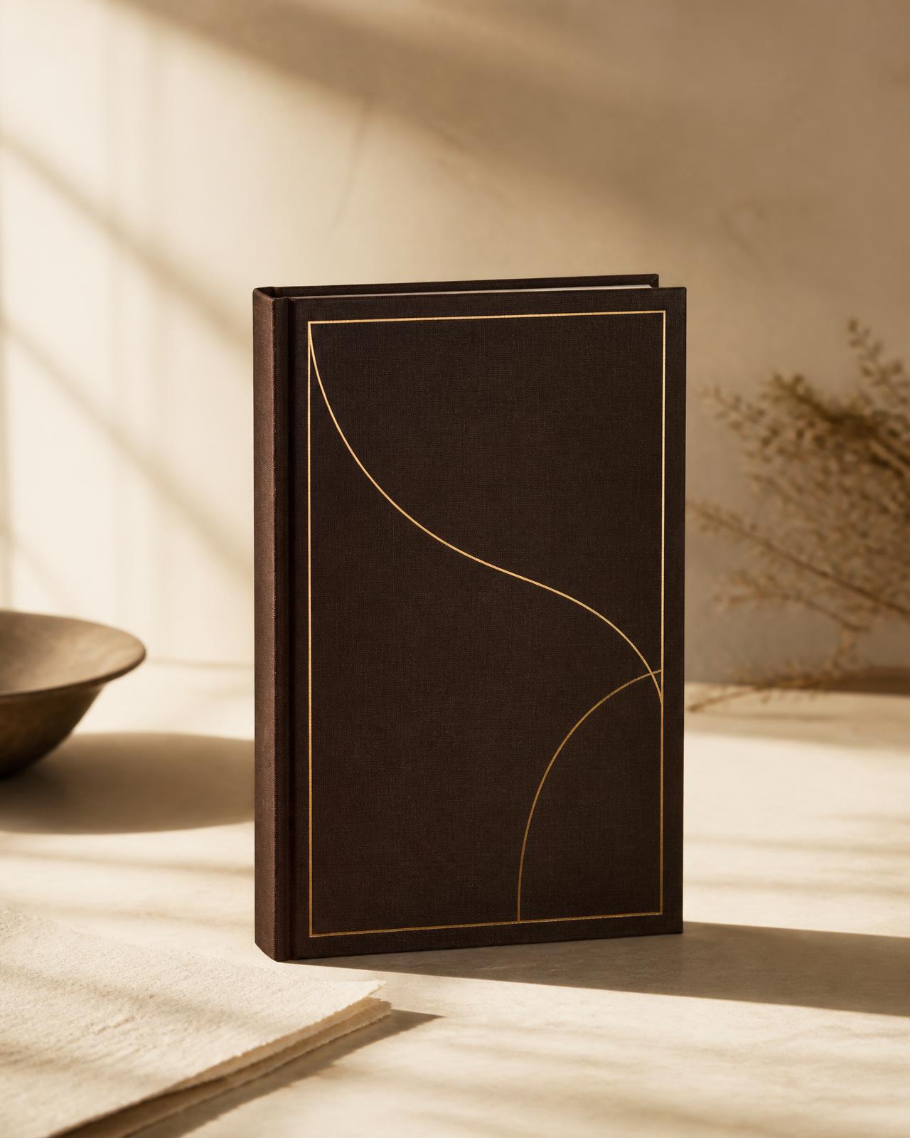 Das VIJUGO Tagebuch als dunkelbraunes Hardcover mit goldener Prägung auf einem Tisch